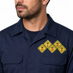 Homem com camisa de trabalho azul-escura e quatro emblemas NR amarelos no peito esquerdo