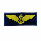 Distintivo bordado azul marinho com asas amarelas, escudo com símbolo médico e coroa
