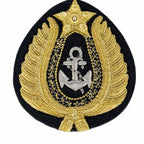 Distintivo oval preto com âncora prateada, folhas douradas e estrela