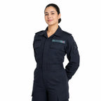 Mulher em uniforme azul-marinho, sorrindo, crachá ALVÉS e símbolo náutico no braço esquerdo