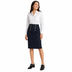 Mulher em look formal com camisa branca, saia azul-marinho e sapatos pretos brilhantes