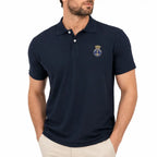 Homem com camisa polo azul marinha bordada com âncora em círculo e coroa