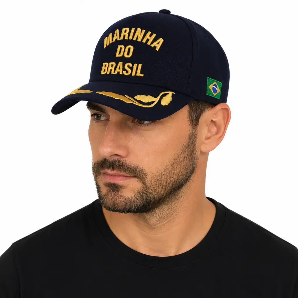 Homem de camiseta preta usando boné escuro Marinha do Brasil dourado com bandeira