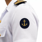 Ombro de uniforme branco com emblema circular azul escuro e âncora dourada