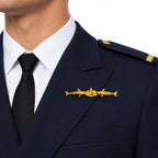 Distintivo dourado com três peixes e estrela central no peito esquerdo do uniforme azul