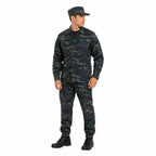 Homem em uniforme camuflado azul e cinza, boné combinando, botas pretas.