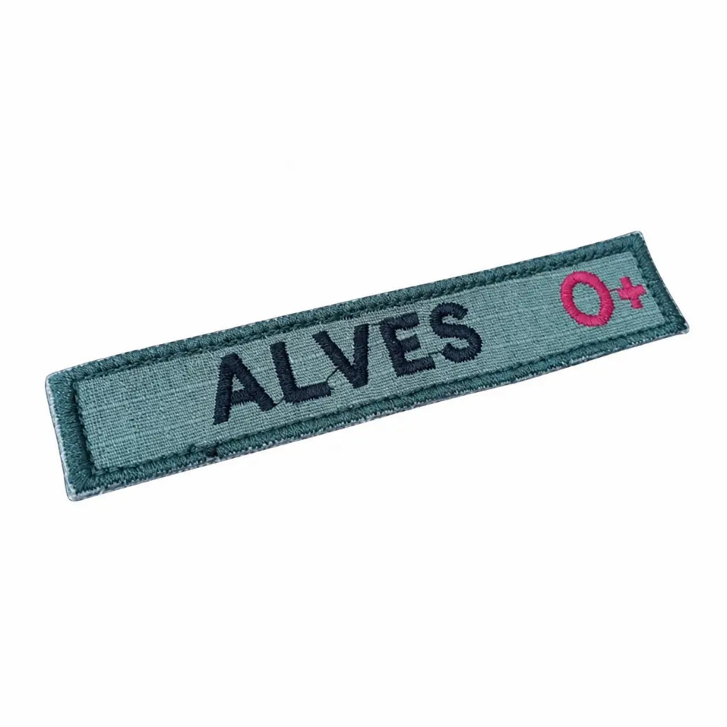 Patch retangular azul-esverdeado com ALVES em letras escuras e O+ rosa