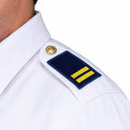 Close-up de camisa branca com braçadeira azul escura e faixas amarelas no ombro