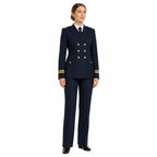 Mulher em uniforme azul-escuro com blazer ajustado, detalhes dourados, camisa branca e sapatos pretos.