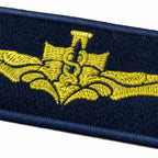 Emblema dourado retangular bordado em azul-marinho com asas centrais