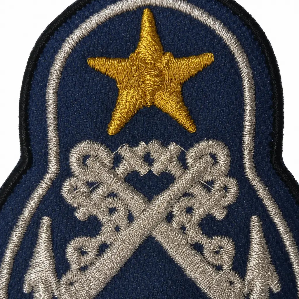 Emblema bordado azul escuro com estrela amarela e bastões cruzados prateados