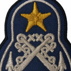 Emblema bordado azul escuro com estrela amarela e bastões cruzados prateados