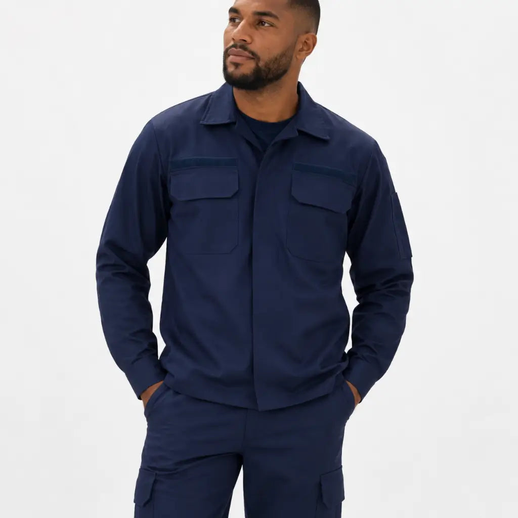 Homem em pé com Conjunto Operativo Op3 Anti-Chama azul escuro, camisa de dois bolsos