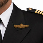 Detalhe de uniforme de piloto com insígnia dourada e listras no ombro