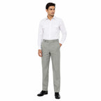 Homem em traje formal: camisa branca, calças cinza claras, cinto e sapatos pretos brilhantes.