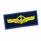 Emblema retangular azul-marinho, âncora amarela bordada em relevo.