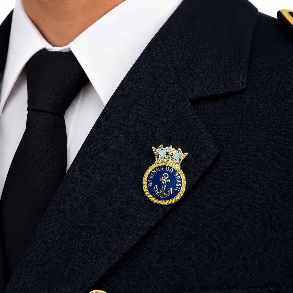 Distintivo circular azul com âncora central, cordão dourado e coroa na lapela