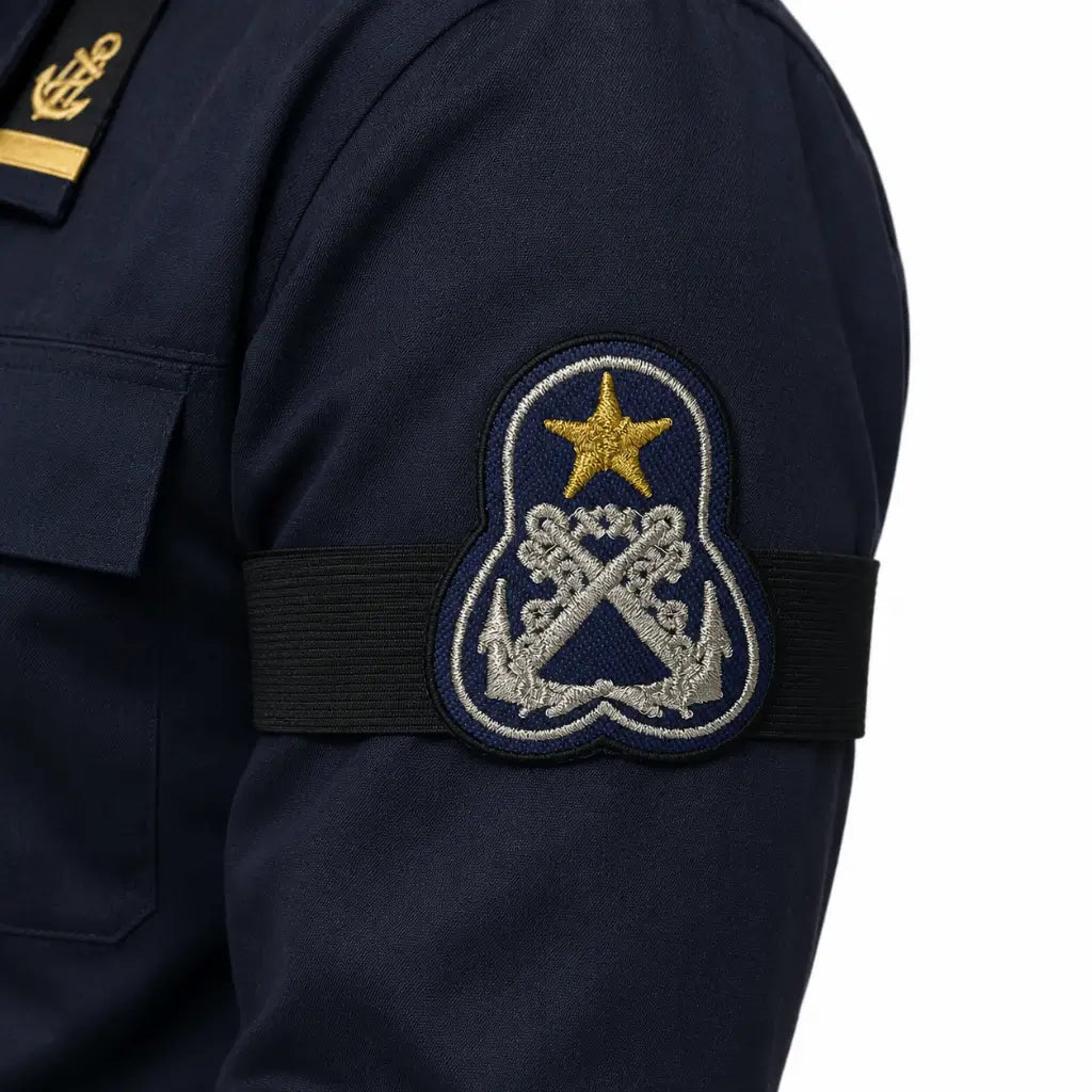 Insígnia azul marinho na manga com faixa preta, estrela dourada e cruzados prateados