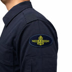 Emblema oval azul marinho na manga com âncora, globo e asas amarelas