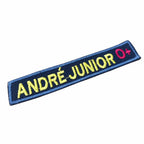 Patch azul retangular com nome ANDRÉ-JUNIOR amarelo e O+ vermelho